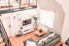 a cool modern space with a loft sleeping space, a living-dining space below, grey and white furniture, a staircase with a black metal frame