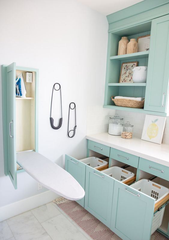 a cool turquoise laundry room with shaker cabinets, a white stone countertops, a hidden ironing board and drawers for laundry
