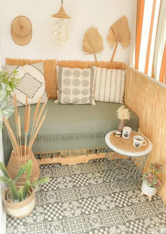 a fab boho balcony that is a perfect reading nook with a pallet sofa with boho pillows, a side table, potted greenery and some boho decor like fronds is a very cool space