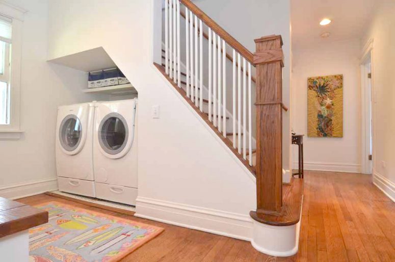 a laundry room with a washing machine and a dryer under the stairs and a shelf for storage is a cool idea