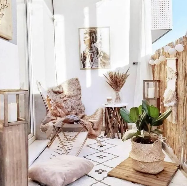 a light-filled boho balcony with a folding chair, boho rugs and pillows, a side table with branch legs, baskets and candle lanterns, paper lamps and macrame