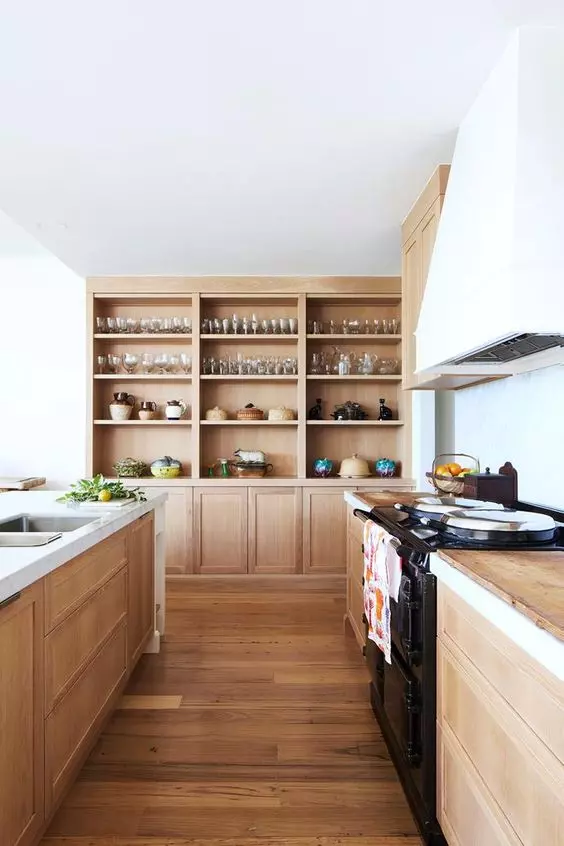 a light-stained wooden kitchen with wooden countertops, built-in wooden storage units and a white hood is very welcoming