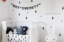 a lovely Scandi nursery with tree decals, a white crib, an iconic Miffy lamp, some art and lots of toys