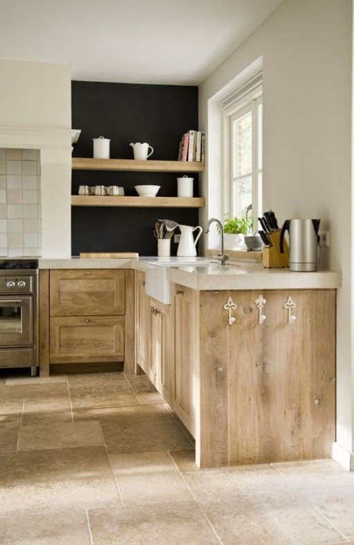 a lovely kitchen with stained shaker style cabinets, a thick stone countertop, a black wall with built-in shelves and a tiled floor