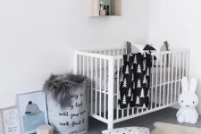 a modern Nordic nursery with a white crib, monochromatic bedding, some artworks, a basket for storage and toys of course