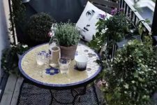 a monochromatic balcony with chairs and a lot of potted greenery is spruced up with a colorful mosaic table