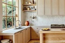 a natural-looking kitchen with light-stained cabinets, a white Zellige tile backsplash, white stone countertops, open shelves and a wooden kitchen island