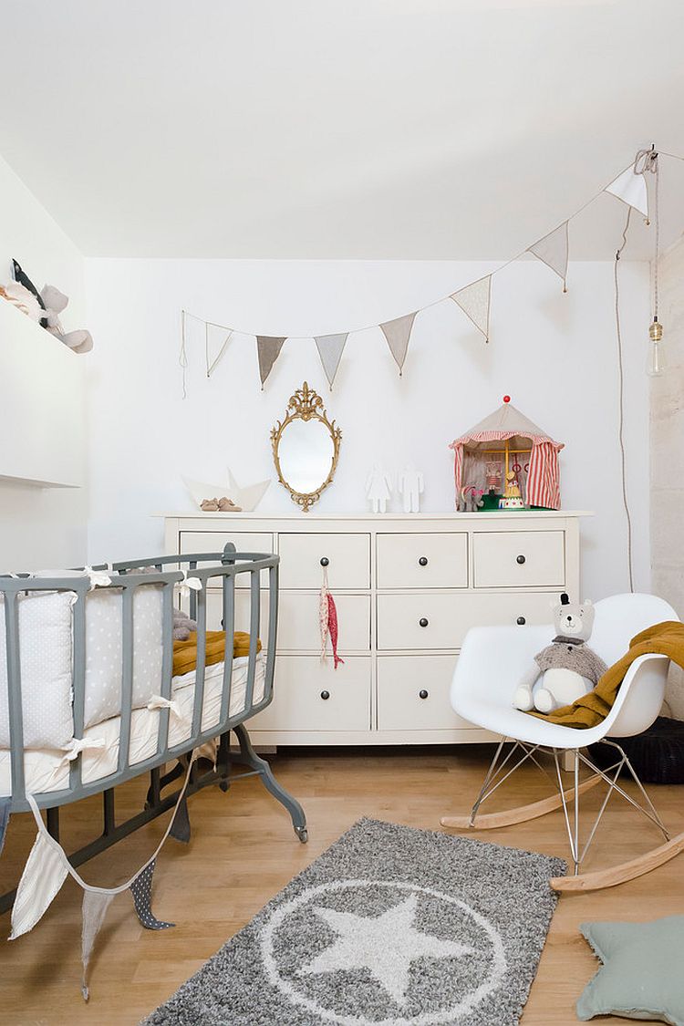 a neutral Scandinavian nursery with a grey vintage crib on casters, an IKEA Hemnes dresser neutral furniture and a neutral banner and a mirror in a gilded frame