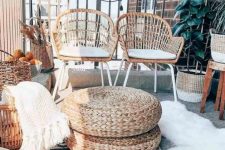 a pretty boho balcony with black and white rugs, faux fur and white blankets, wicker chairs, candle lanterns and jute poufs, potted plants is amazing for spending time here