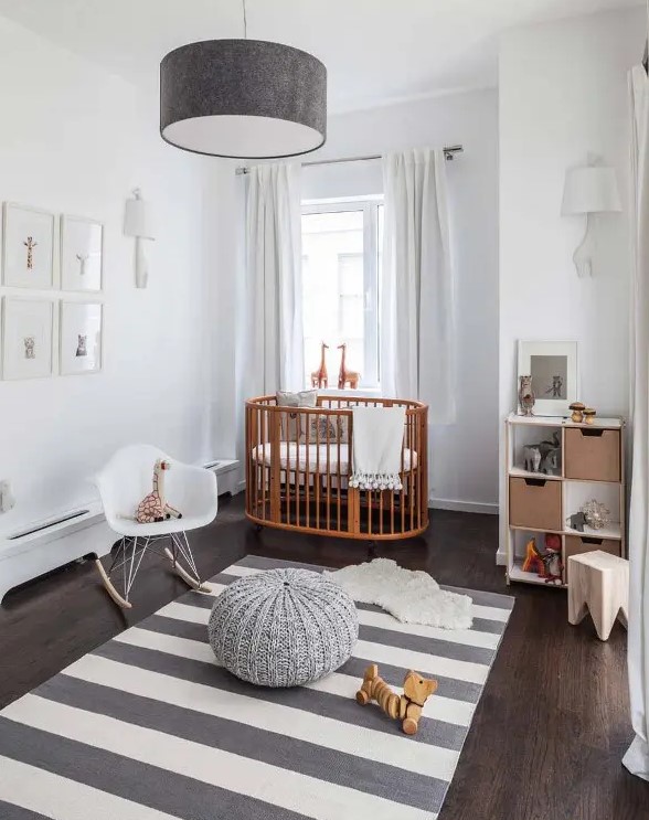 a serene Scandi nursery with a rich stained crib and all the rest done in grey and white, with a grid gallery wall and some lovely toys