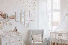 a serene Scandinavian nursery with white furniture, a woven pendant lamp, a polka dot wall, a gallery wall and some pretty toys