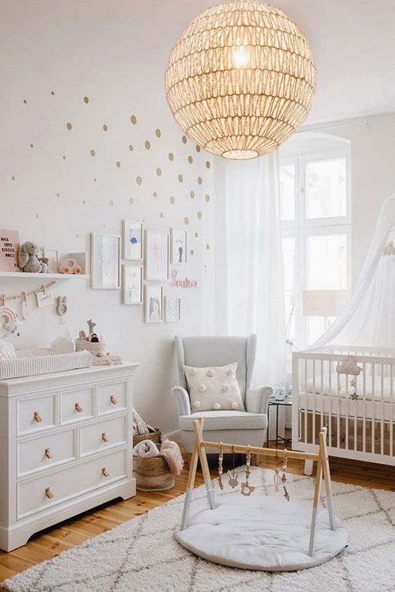 a serene Scandinavian nursery with white furniture, a woven pendant lamp, a polka dot wall, a gallery wall and some pretty toys