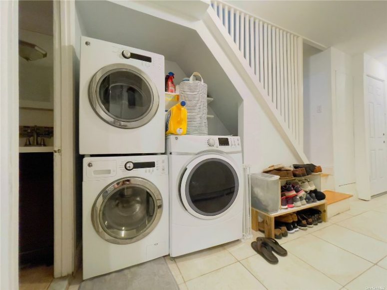 a small and cool laundry built under the staircase, with some storage shelves and a couple of machines