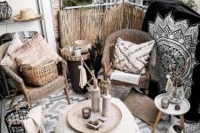 a small black and white boho balcony with a black printed pillow, rattan chairs, a woven pouf with macrame, lots of vases, rugs, candles and baskets is amazing