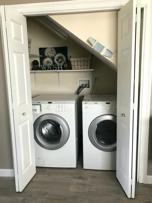 a small laundry room under the stairs, with folding doors, a built in shelf and a washing machine and a dryer