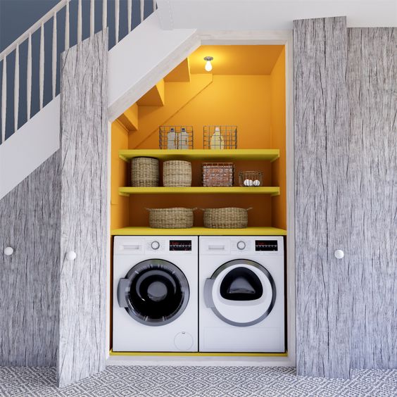 a small modern laundry room with yellow walls, built in shelves, a washing machine and a dryer, some lights is cool