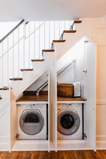 a small under the stairs laundry with a washing machine and a dryer, with a built-in shelf and several doors to hide them
