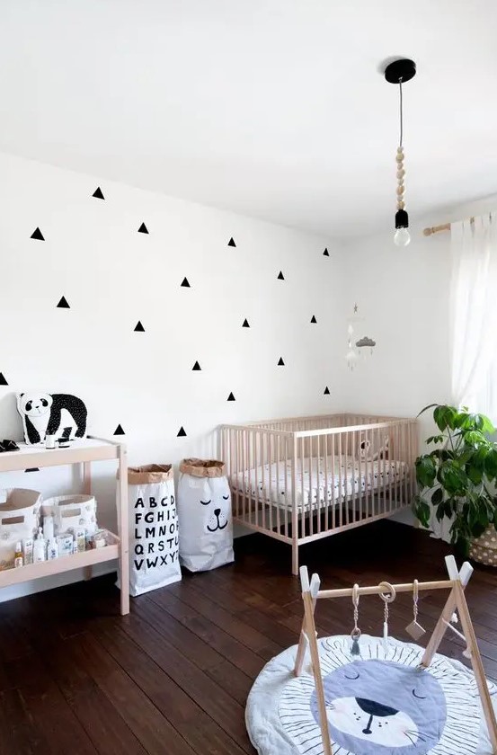 a stylish Nordic nursery with an accent wall, stained furniture, a pendant bulb, some toys and a potted plant is a lovely space