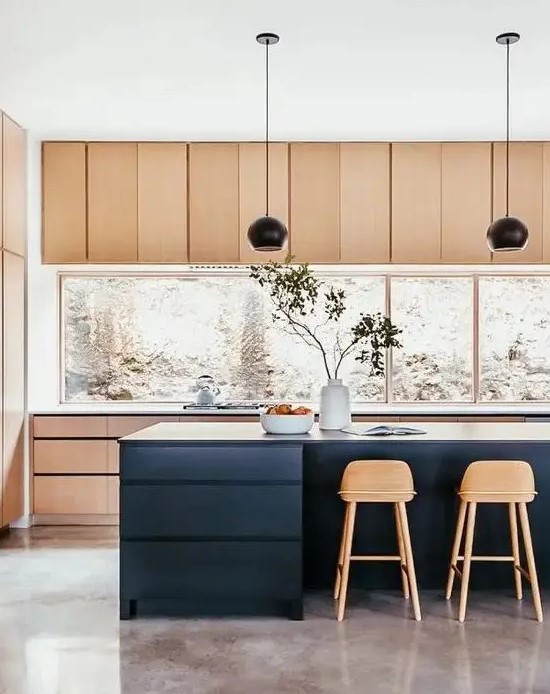 a stylish light stained kitchen with a large window backsplash, a navy kitchen island, black pendant lamps and tall stained stools is perfection