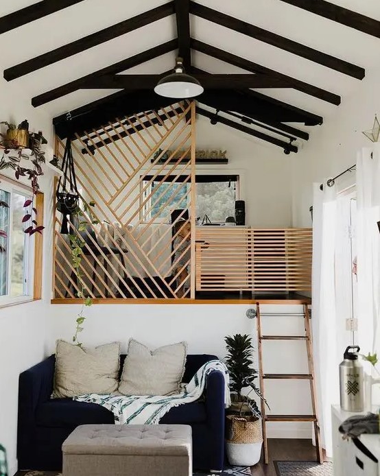 a tiny contrasting house with a living room and a bedroom up the stairs, with wooden screens to cover the space