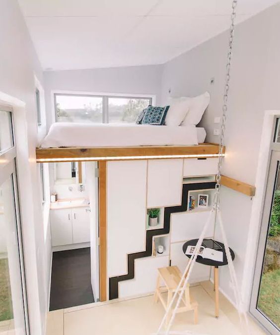 a tiny modern home with a loft bedroom, a storage unit that doubles as a bathroom and a kitchen and dining space below
