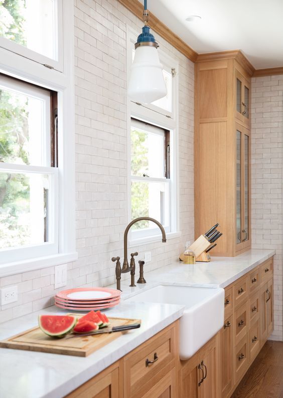 an elegant kitchen with light-stained shaker style cabinets, a white subway tile backsplash, white stone countertops