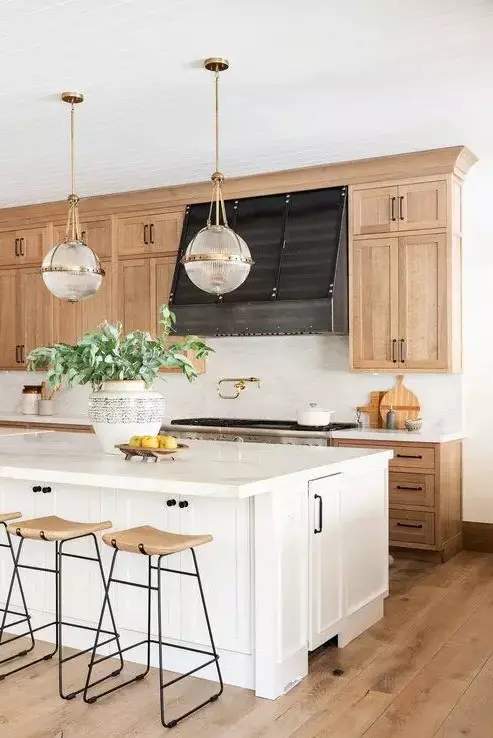 an inviting farmhouse kitchen with light-stained shaker style cabinets, white stone countertops and a white backsplash, wooden stools and a white kitchen island