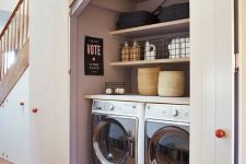 an under stairs laundry with shiplap doors, built-in shelves and a washing machine and a dryer is a stylish and comfortable to use space