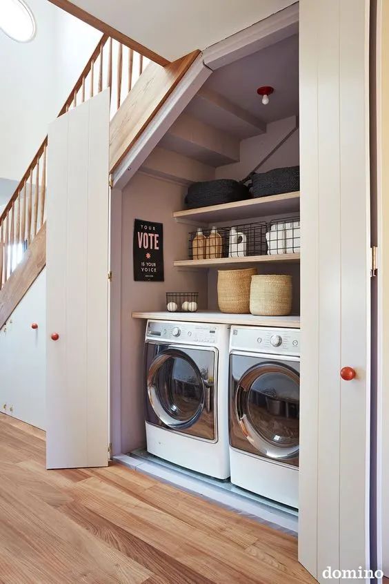 an under stairs laundry with shiplap doors, built-in shelves and a washing machine and a dryer is a stylish and comfortable to use space