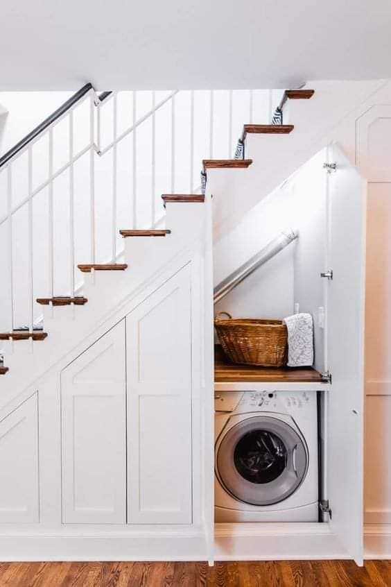 an under stairs space turned into a small but practical laundry - a washing machine and a dryer, baskets for storage
