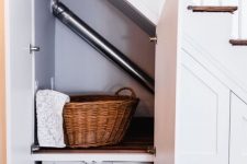 an under the stairs built-in laundry space with a built-in shelf for storage and a washing machine plus doors to hide it