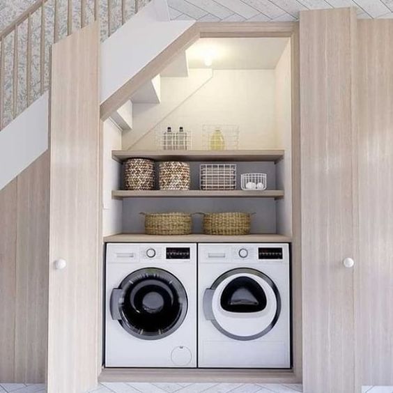 an under the stairs laundry with lights, built-in shelves, a washing machine and a dryer, some baskets for storage