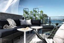 02 a beautiful contemporary seaside terrace with dark wicker furniture and black upholstery, white coffee tables and a chair, black and white pillows