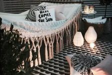 04 a black and white outdoor nook with a hammock, printed pillows, baskets with greenery, candles and candle lanterns