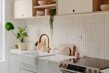 04 a chic kitchen in dove grey and light-colored plywood, with white countertops and a white skinny tile backsplash