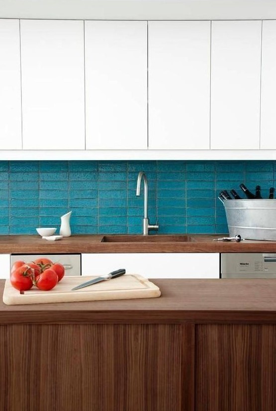 a chic kitchen in white and stained wood, with a turquoise skinny tile backsplash is very stylish