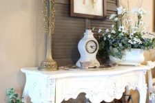 06 beautiful vintage cottage decor with taupe shutters, a refined carved console table, vintage books, candles and table lamps