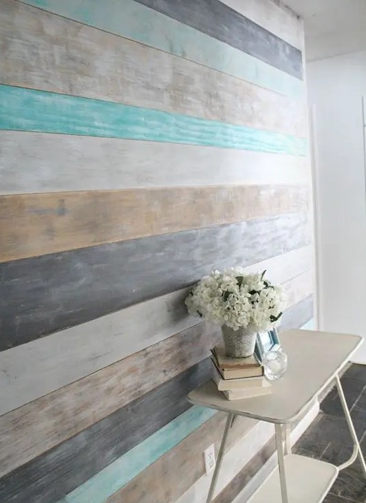 a wall covered with shabby and washed out wood in planks of different colors - beige, white, grey and graphite grey
