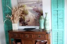 07 bold turquoise shutters on both sides of a console bring a beach feel to the space
