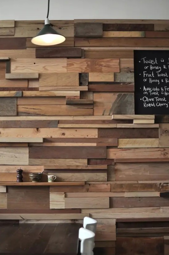 a unique accent wall done with lots of wooden slabs and planks in various colors adds a rustic and industrial touch