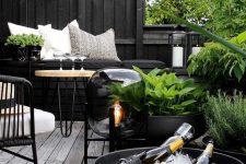10 a dark Nordic terrace with black walls, planters and bowls, metal and wooden furniture, a catchy floor lamp and greenery that refreshes the space