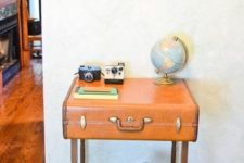12 a pretty console table made of a vintage suitcase placed on legs and with a shelf, with cameras and a globe is a lovely idea