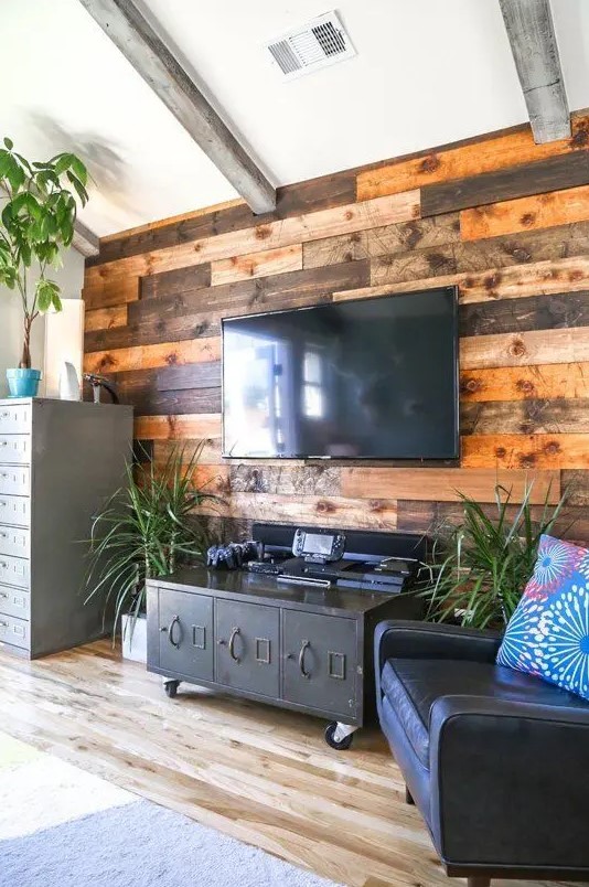 a weathered and stained wood accent wall softens the industrial inspired living room with vintage touches