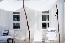 13 a lovely and relaxed deck with white metal and wicker furniture, neutral textiles, a black stool and sticks with white curtains
