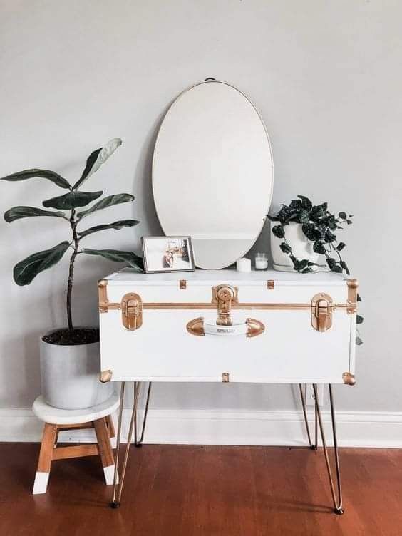 a pretty console table of a beautiful white vintage suitcase with gold detailing, on hairpin legs, with a mirror and some plants