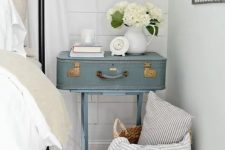 14 a serenity blue nightstand of a vintage suitcase on trestle legs, with a pastel sconce and some blooms