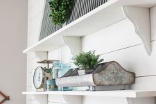 14 vintage white shelves with potted greenery and a greenery wreath, vintage items and a grey shutter for lovely vintage rustic look