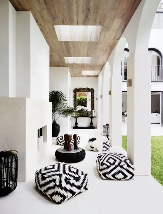 a lovely patio with a concrete fireplace with pillar candles, black and white poufs and black candle lanterns