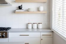 16 a serene white kitchen with a skinny tile wall, creamy cabinets, open shelves and brass fixtures for more chic