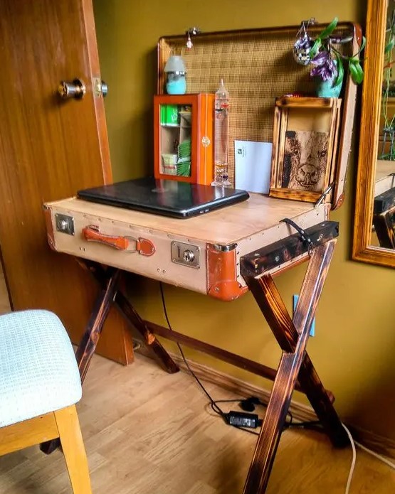 a small desk made of a vintage suitcase on trestle legs and a tabletop inserted, with some decor and a photos